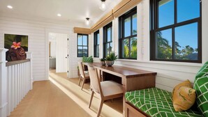 Una cocina moderna con encimera de madera, armarios blancos y ventanas amplias.