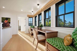 Una cocina moderna con encimera de madera, armarios blancos y ventanas amplias.