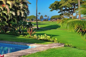 Un campo de golf bien cuidado con vistas claras al océano de fondo.