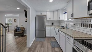 Una cocina moderna con armarios blancos, electrodomésticos de acero inoxidable y encimera de granito.