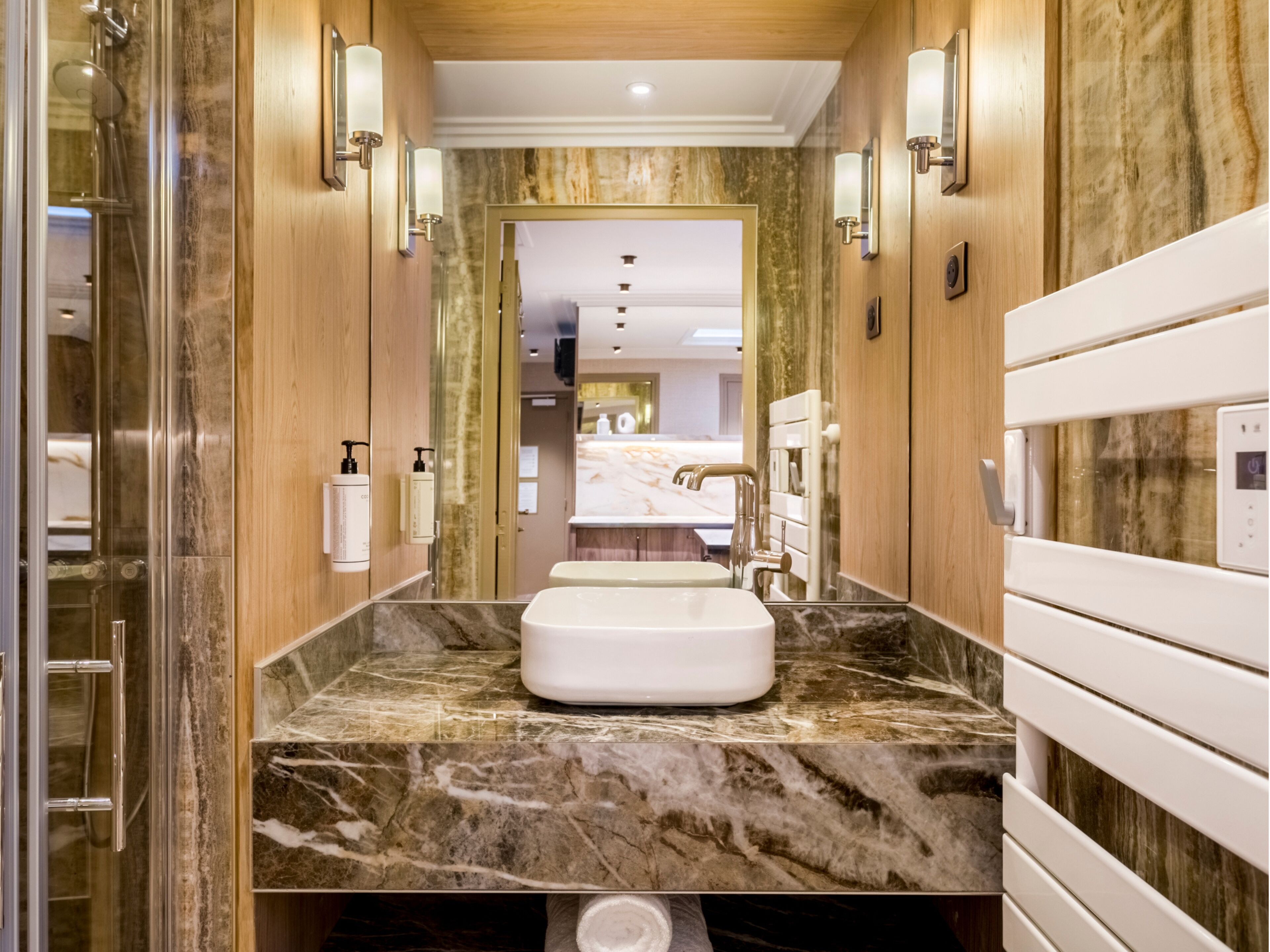 A modern bathroom with a marble countertop, a built-in sink, and a shower enclosure.