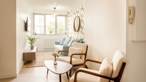 Ein Wohnzimmer mit einer Couch, zwei Sesseln, einem Couchtisch und einer Topfpflanze.
