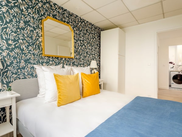 A bedroom with a bed, a nightstand, a lamp, and a wardrobe. - Family Suites - Viala I-II-IV (Paris)
