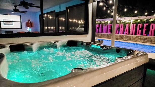 A hot tub with a view of a pool and a sign reading "GAME CHANGER."