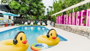A swimming pool with inflatable ducks and a rainbow float ring.
