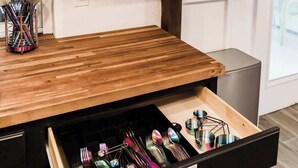 Una cocina con armarios de madera, una encimera y un cajón con utensilios.