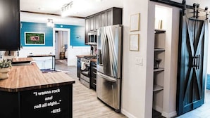 A modern kitchen with a central island, stainless steel appliances, and a blue accent wall.