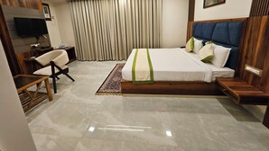 A modern hotel room with a large bed, a desk, a chair, a television, and a ceiling fan. - HOTEL MAA LAXMI PALACE (Deoghar)