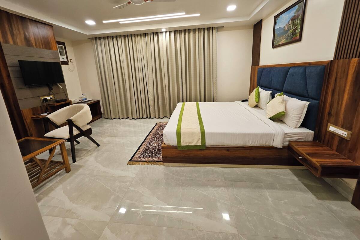 Quarto de hotel moderno com uma cama grande, uma escrivaninha, uma cadeira, televisão e ventoinha no teto.
