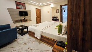 A modern hotel room with a bed, a blue sofa, a TV, and a wooden wardrobe. - HOTEL MAA LAXMI PALACE (Deoghar)