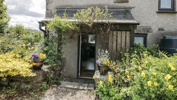 A stone house with a wooden door and a small porch. - Threagill (Carnforth)