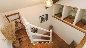 A wooden staircase with a white railing, a hanging light fixture, and two framed photographs on the wall. - 18 Main Street (Fishguard)