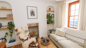 A cozy living room with a fireplace, a rocking chair, a sofa, and a wooden coffee table. - 18 Main Street (Fishguard)