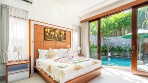 Une chambre dotée d’un grand lit, d’un tableau représentant des éléphants, d’une vue sur une piscine et d’une porte-fenêtre coulissante donnant sur un jardin.