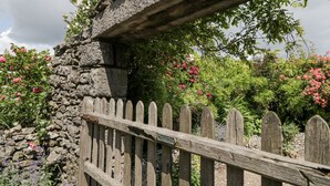 A stone wall with a wooden fence and lush greenery.
