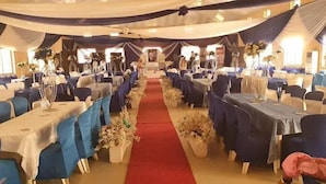A banquet hall with rows of tables and chairs, a red carpet aisle, and draped curtains. - Jam Bed Hotels (Abeokuta)