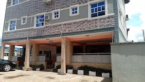 A multi-story building with a covered entrance, columns, and a car parked in front. - Jam Bed Hotels (Abeokuta)
