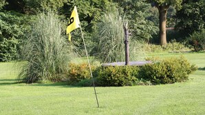 A golf flag on a flagpole, surrounded by grass and bushes. - Apartment 'Haarkotten' with Private Terrace, Shared Garden and Wi-Fi (Steinfurt)