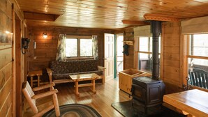 L’intérieur chaleureux d’un chalet avec des murs en bois, un canapé, une table et un poêle à bois.