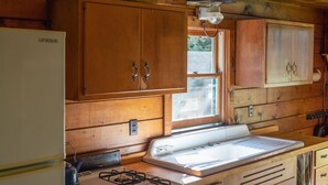 Une cuisine avec des meubles de rangement en bois, une cuisinière et un évier.