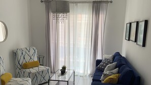 Un salon moderne comprenant un canapé, deux fauteuils, une table basse et un meuble pour la télévision.