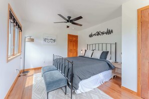 A bedroom with a bed, a bench, a ceiling fan, a door, a wall-mounted light, and a framed picture. - Slate View Dreams,  Close to CB, hot tub, deck, patio, firepit, views! (Crested Butte)