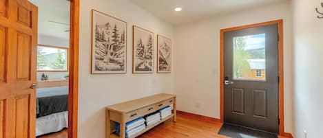 A hallway with wooden flooring, a bench with towels, and framed pictures on the wall.