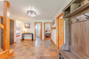 A hallway with a checkered floor, wooden doors, a table with a lamp, and a bed in the distance. - Slate View Dreams,  Close to CB, hot tub, deck, patio, firepit, views! (Crested Butte)