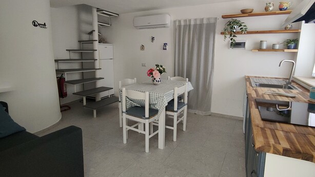 A compact living space with a dining area, kitchenette, and a staircase leading to an upper level. - Casa Pitturini comfortable apartment in quiet area 500 m from the sea (Marciana Marina)