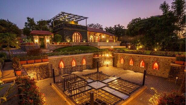 A modern house with a courtyard, stone walls, and a glass-roofed structure. - Lavender Villa by Ebony Stays – Peaceful 3 BHK Getaway in Nashik (Gangavhare)