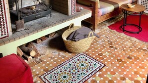A cozy living room with a traditional fireplace, a sofa with cushions, a small table, and a patterned rug.