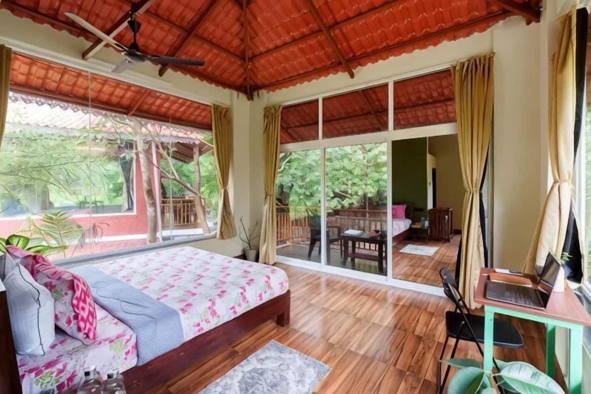 Ein Schlafzimmer mit einem Bett, einem Schreibtisch, einem Stuhl und einem großen Fenster.