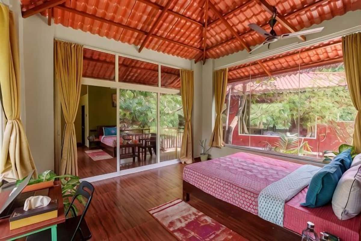 Ein Schlafzimmer mit Bett, Schreibtisch, Stuhl, Fenster und einer Schiebetür.