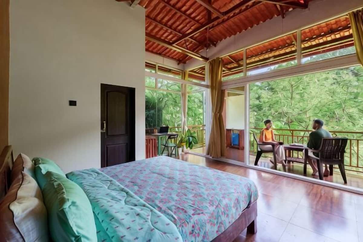 Ein Schlafzimmer mit Bett, einer Tür und einem Balkon mit Stühlen und einem Tisch.