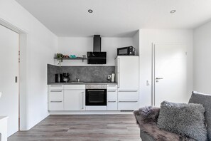 Una cocina moderna con armarios blancos, un horno negro y un microondas.