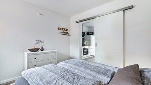 Et soveværelse med seng, kommode, spejl og skydelåge til skab.