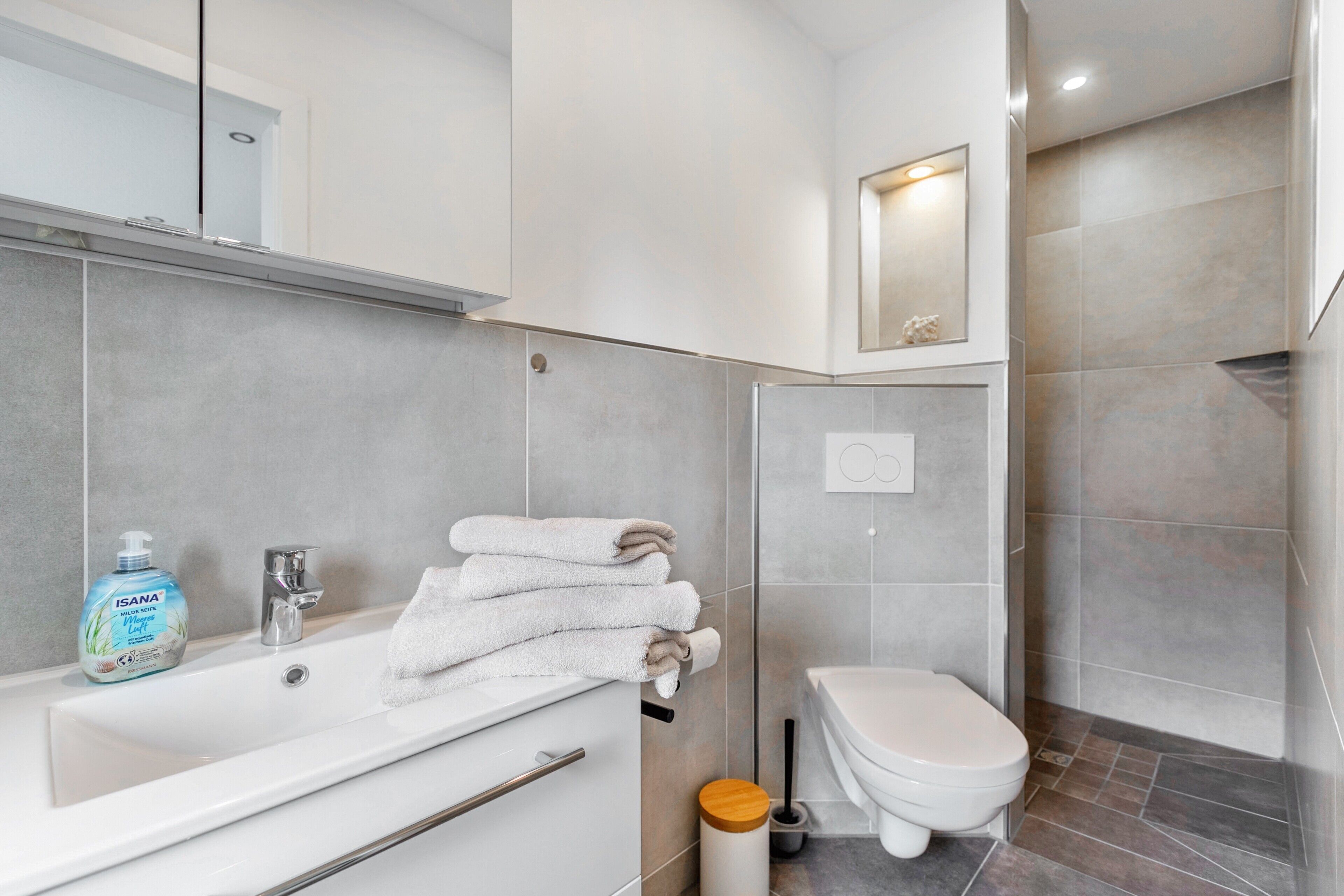 A modern bathroom with a bathtub, toilet, and a mirror above the sink.
