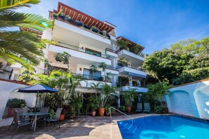 A multi-story building with balconies, a swimming pool, and outdoor seating. - Casa Robalo (Puerto Vallarta)