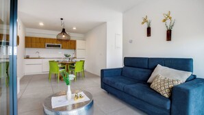A modern living room with a blue sofa, a round coffee table, and a dining area with green chairs. - La Lita. Panoramic Sea View- Fast Wi-Fi -Free Parking (Šmarje pri Kopru)