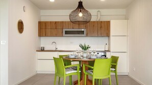 A modern kitchen with wooden cabinets, a stainless steel microwave, and a dining table with green chairs. - La Lita. Panoramic Sea View- Fast Wi-Fi -Free Parking (Šmarje pri Kopru)