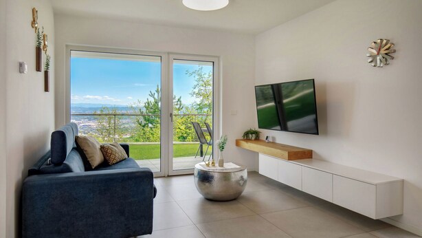 A modern living room with a sofa, a round side table, a flat-screen TV, and a sliding glass door leading to a balcony. - La Lita. Panoramic Sea View- Fast Wi-Fi -Free Parking (Šmarje pri Kopru)