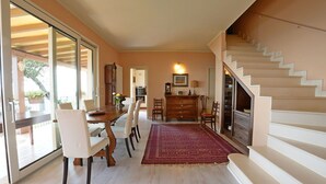 Ein Essbereich mit einem Holztisch und -stühlen, einem roten Teppich und einer Treppe mit weißen Stufen.