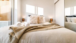 Una habitación de hotel moderna con una cama grande, techo de madera y un espejo amplio.