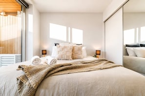 A modern hotel room with a large bed, a wooden ceiling, and a large mirror.