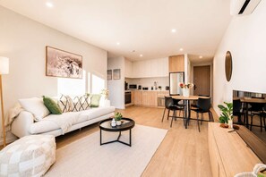 A modern living room with a sofa, coffee table, and dining area.