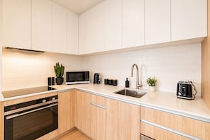 Una cocina moderna con microondas, tostadora, pileta y una planta en maceta.