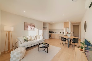 A modern living room with a sofa, coffee table, and dining area.