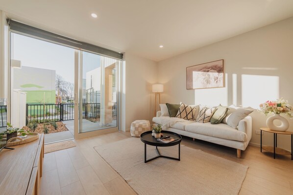 A modern living room with a sofa, coffee table, and a view of the outdoors.