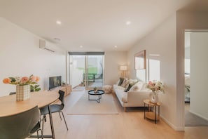 A modern living room with a dining area, a sofa, a coffee table, and a TV.