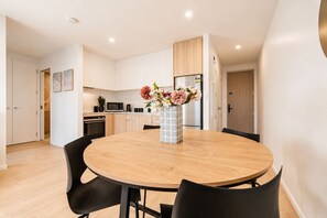 A modern kitchen with white cabinets, a microwave, and a refrigerator.